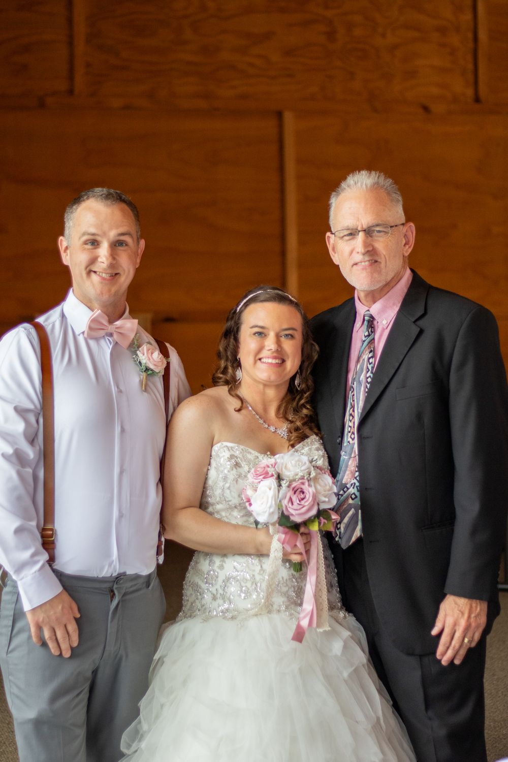 Bride and groom smiling with their wedding officiant.