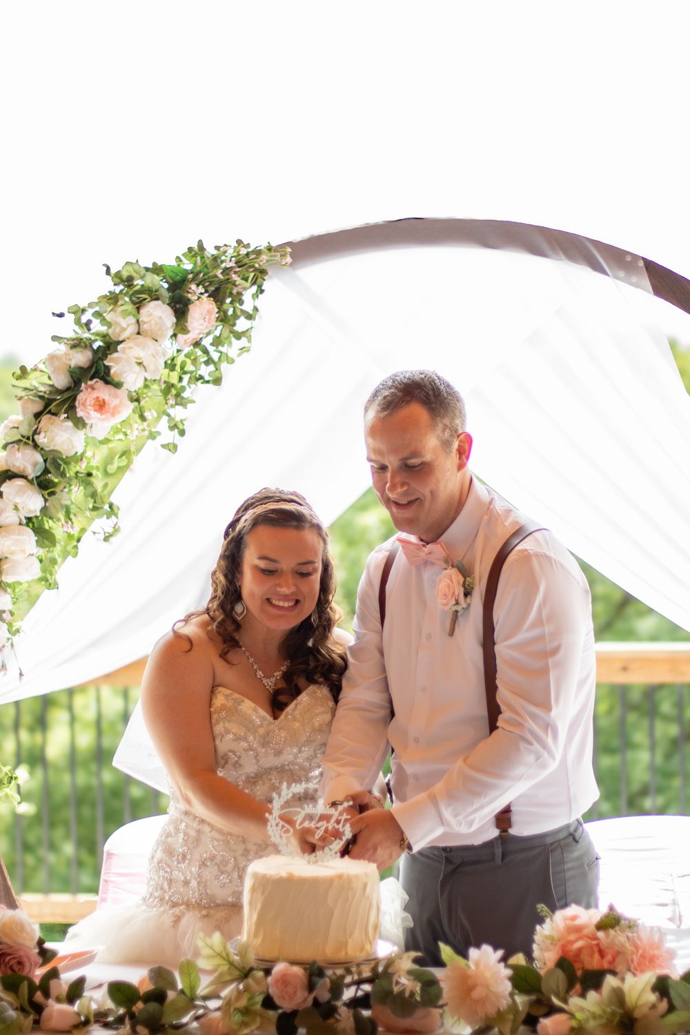 Bride and groom cutting their wedding cake outside.