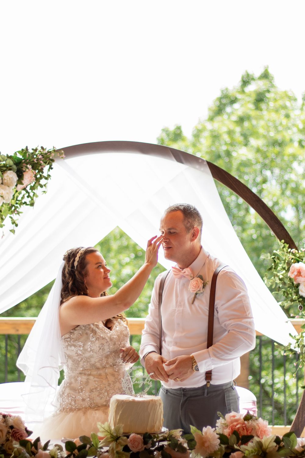 Bride putting cake on the grooms face at their wedding.