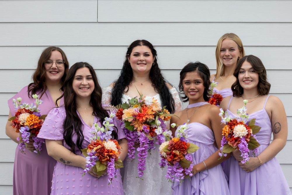 Bride and bridesmaids smiling while holding their bouquets outside.