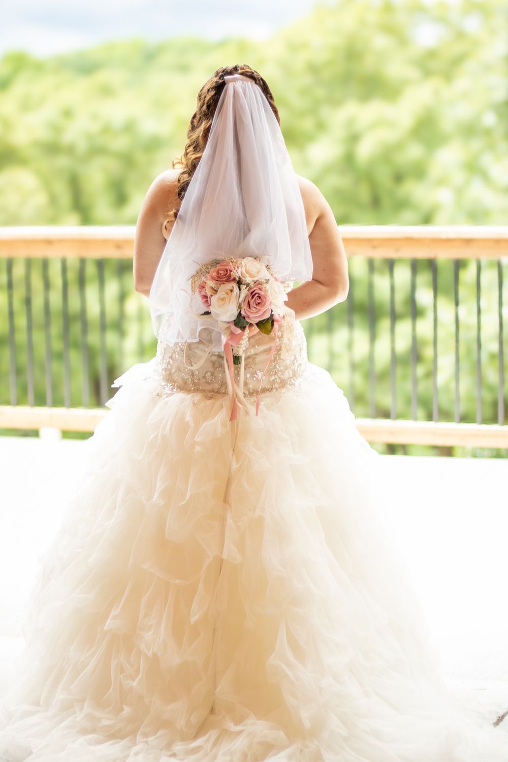 Bride holding bouquet looking at the view from wedding venue.