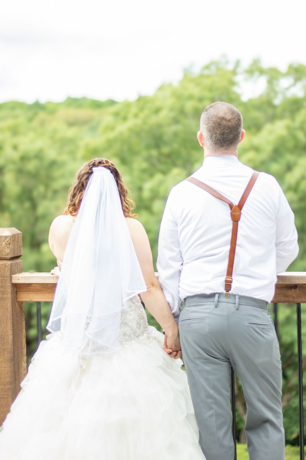 Bride and groom holding hands looking at the view of their outside wedding venue.