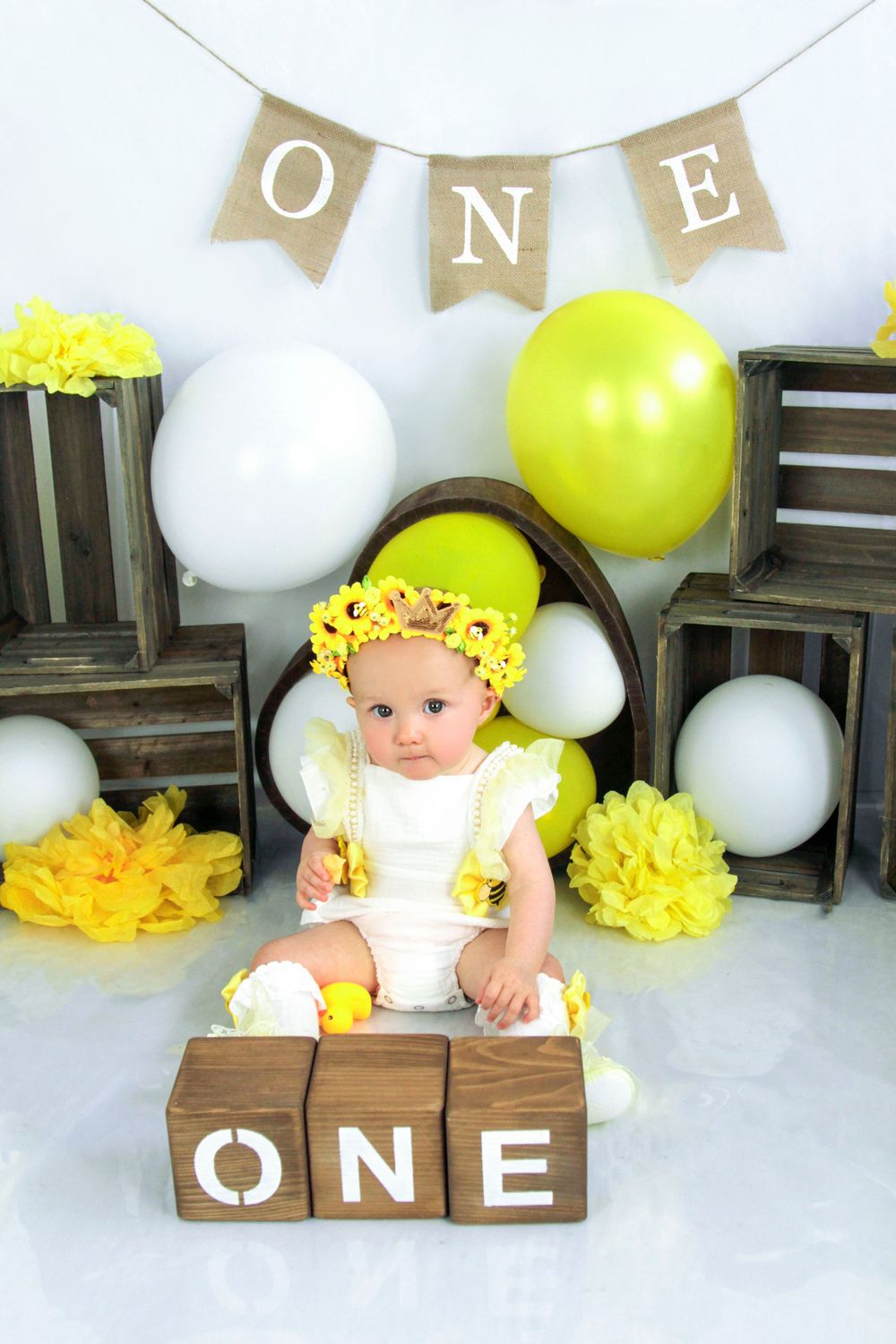 Yellow and white themed first birthday setup with wooden blocks and festive decorations.