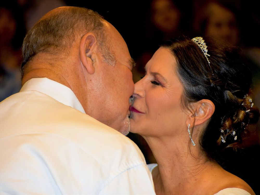 A couple shares a tender kiss while dancing together at what appears to be a formal event or celebration.