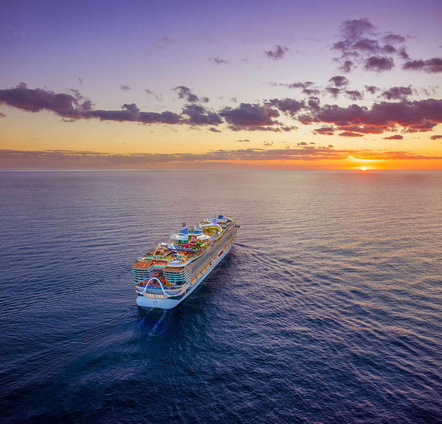 Royal Caribbean cruise ships sail in formation across blue ocean waters during a fleet showcase event.