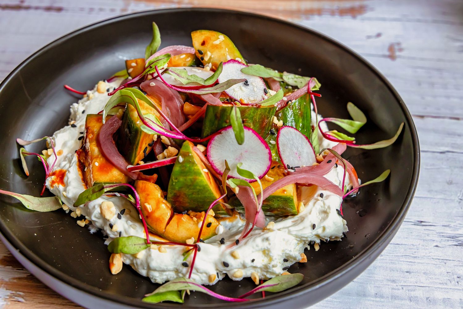Colorful plated dish with rice and vegetables on dark ceramic plate.