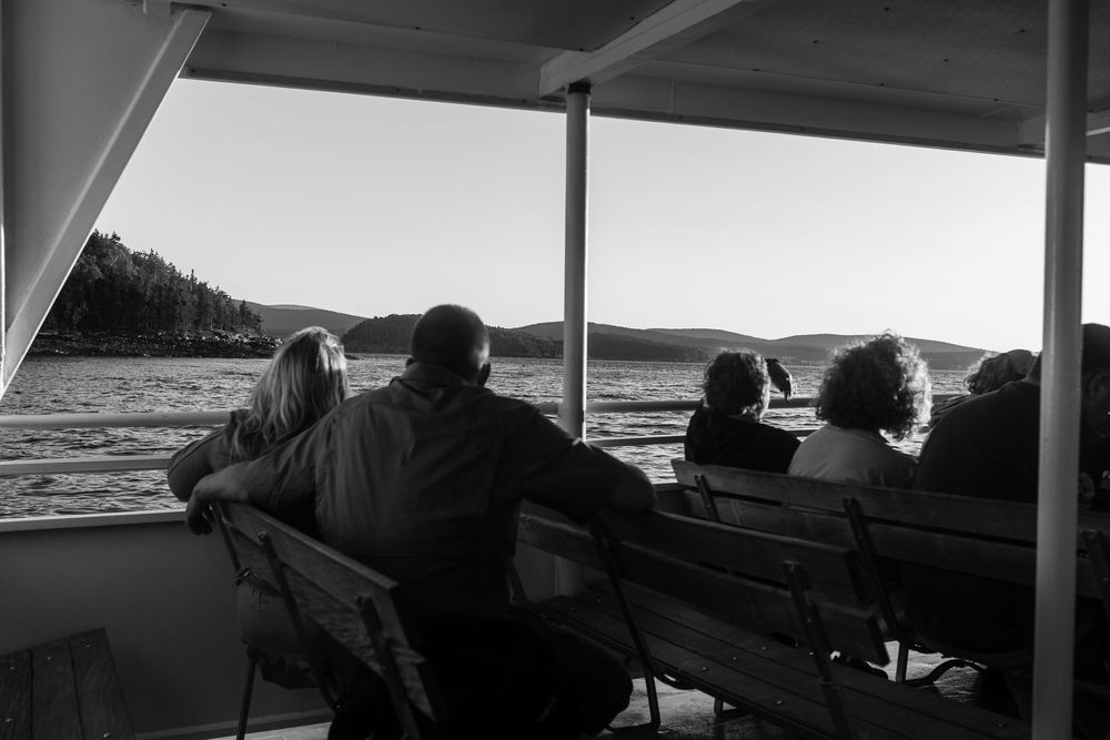 A series of black and white photographs showing boat passengers enjoying views of the coastline from different angles.