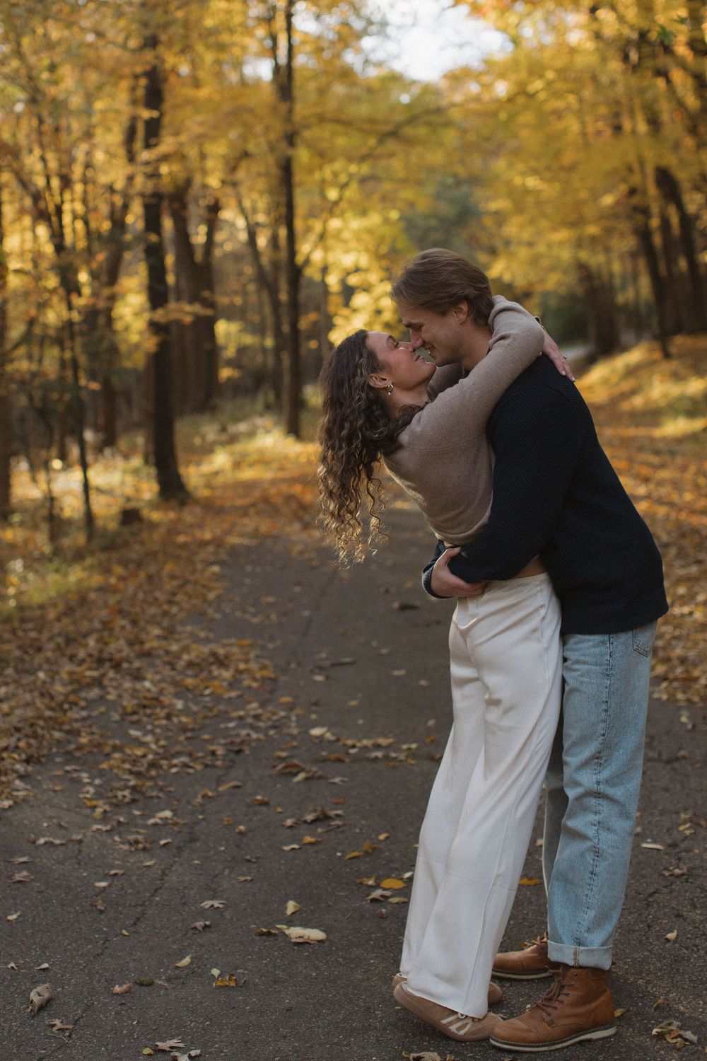A tender embrace on a forest path surrounded by golden autumn trees.