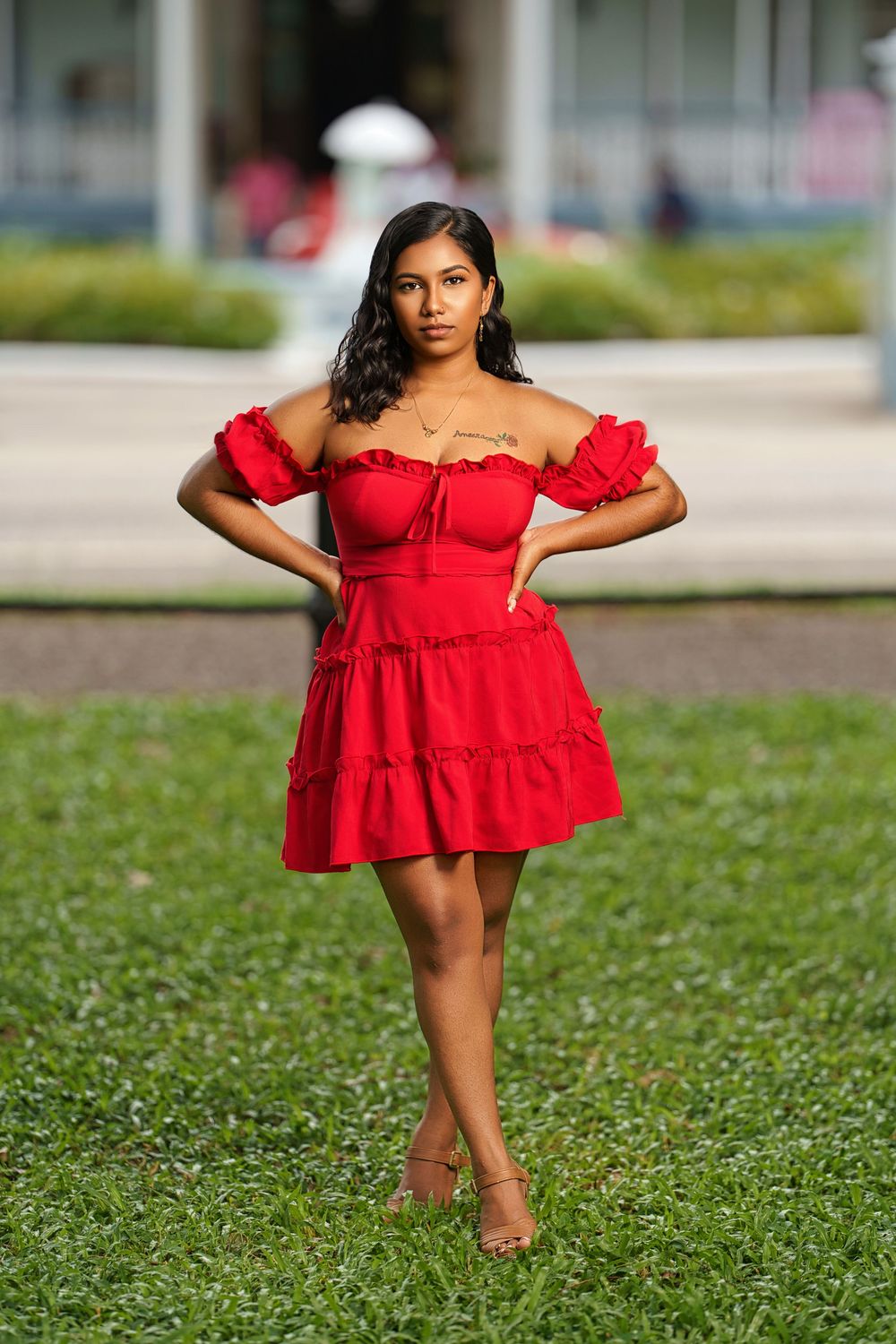 A red off-shoulder mini dress with ruffles is styled for a summer photoshoot outdoors.