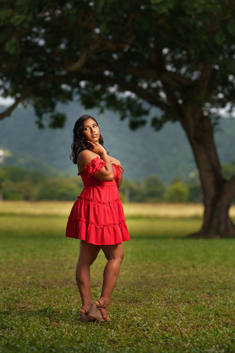 A series of outdoor portraits showing a person in a red dress sitting and posing on grassy ground.