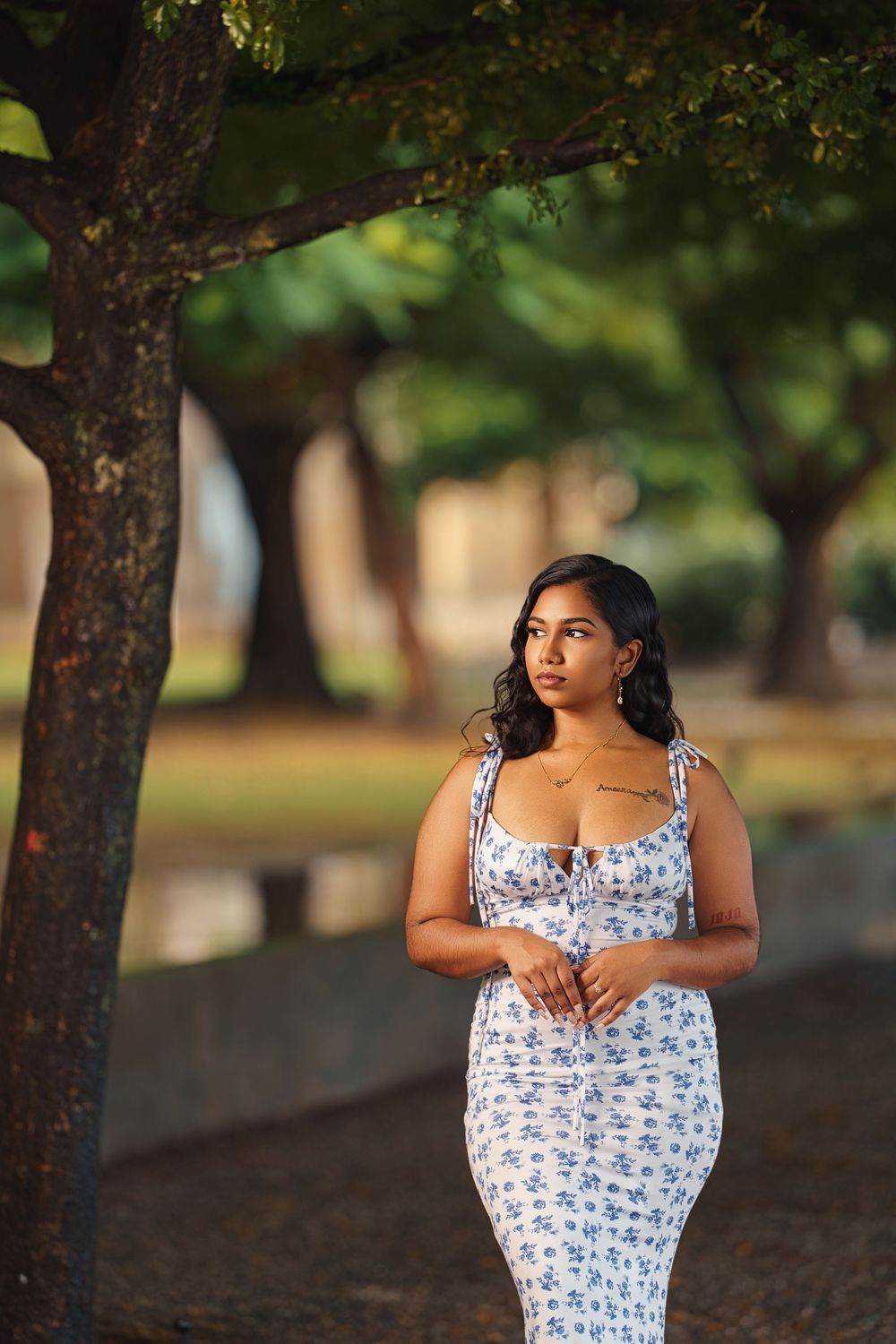 A flowing blue and white floral dress is modeled against a natural outdoor backdrop with trees.