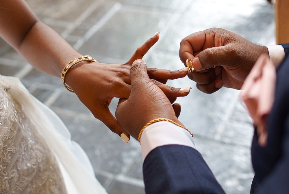 Close-up of hands exchanging wedding rings during a marriage ceremony.