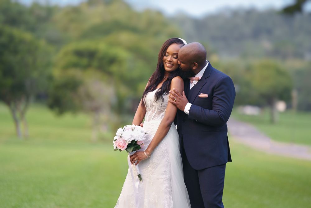 Romantic wedding couple embraces on a lush green golf course during their special day.