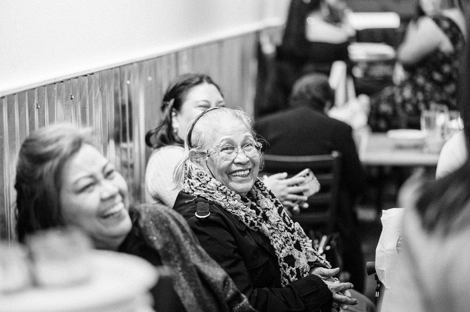 black and white photo showing people laughing and expressing joy in various candid moments.