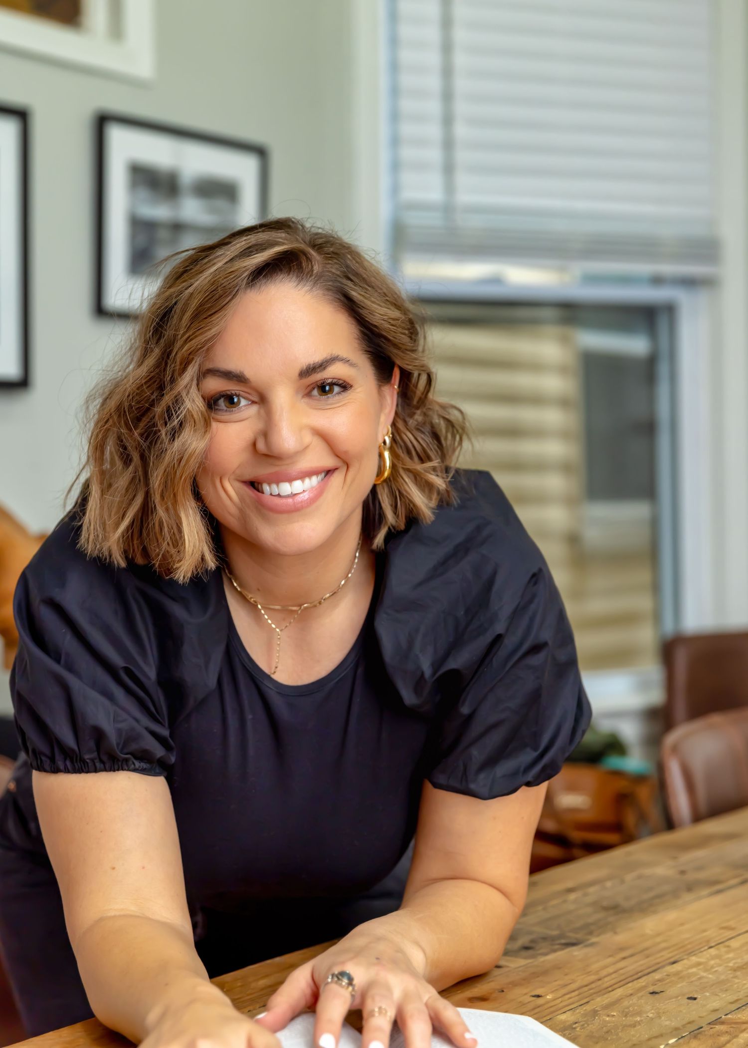 Professional portrait session at wooden table in bright interior setting.