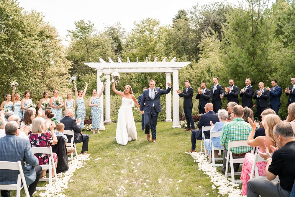 Couple celebrates as they walk down the aisle at their summer wedding ceremony at Fishermen's Inn in Elburn, Illinois.