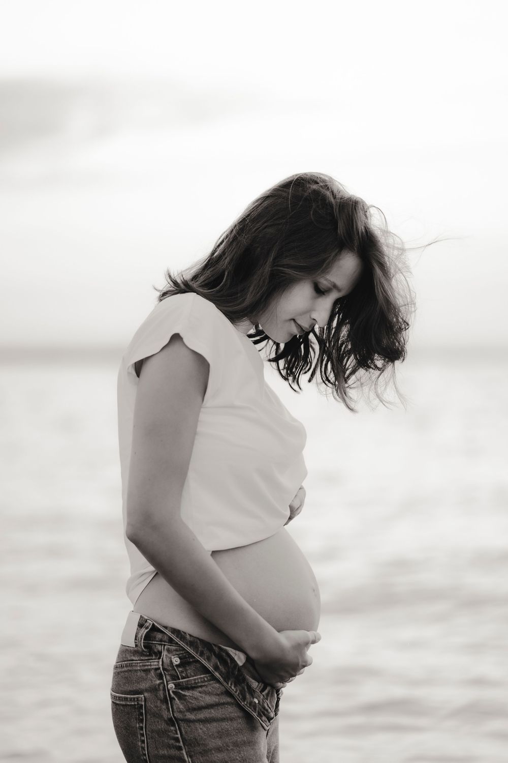 Beautiful fine art portrait of a radiant mother-to-be posing on Caorle beach at sunset.