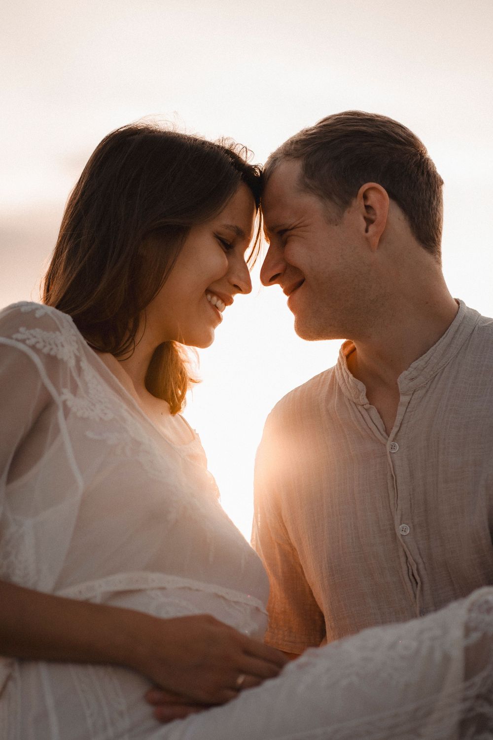 Romantic couple session with a man kissing his pregnant partner's forehead on Caorle coast.