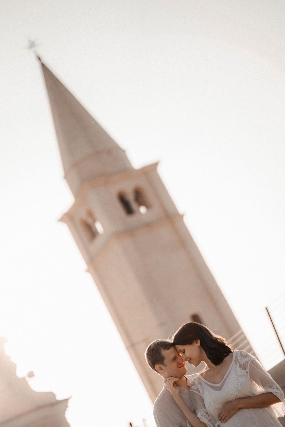 Carefree foreign couple sharing a sweet hug on the wide, sandy coast of Caorle at golden hour.