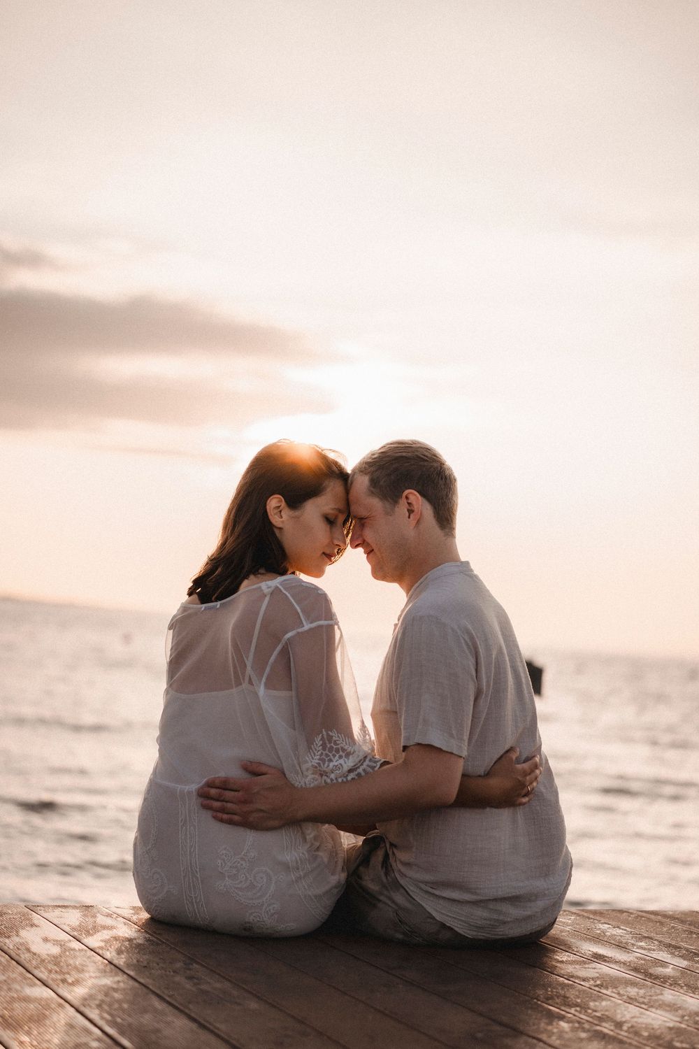 Romantic couple walking hand in hand on the wet sand, reflecting the beautiful colors of a Caorle sunset.