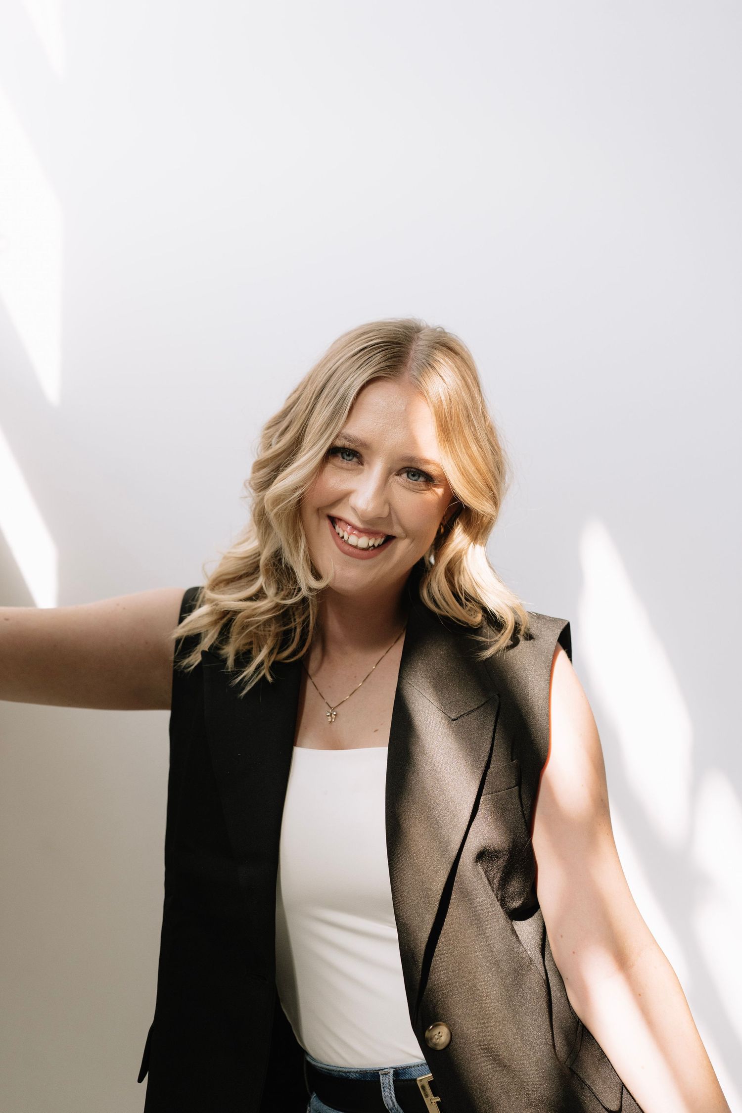 Professional portrait series showing a warm smile and casual business style against a light background.
