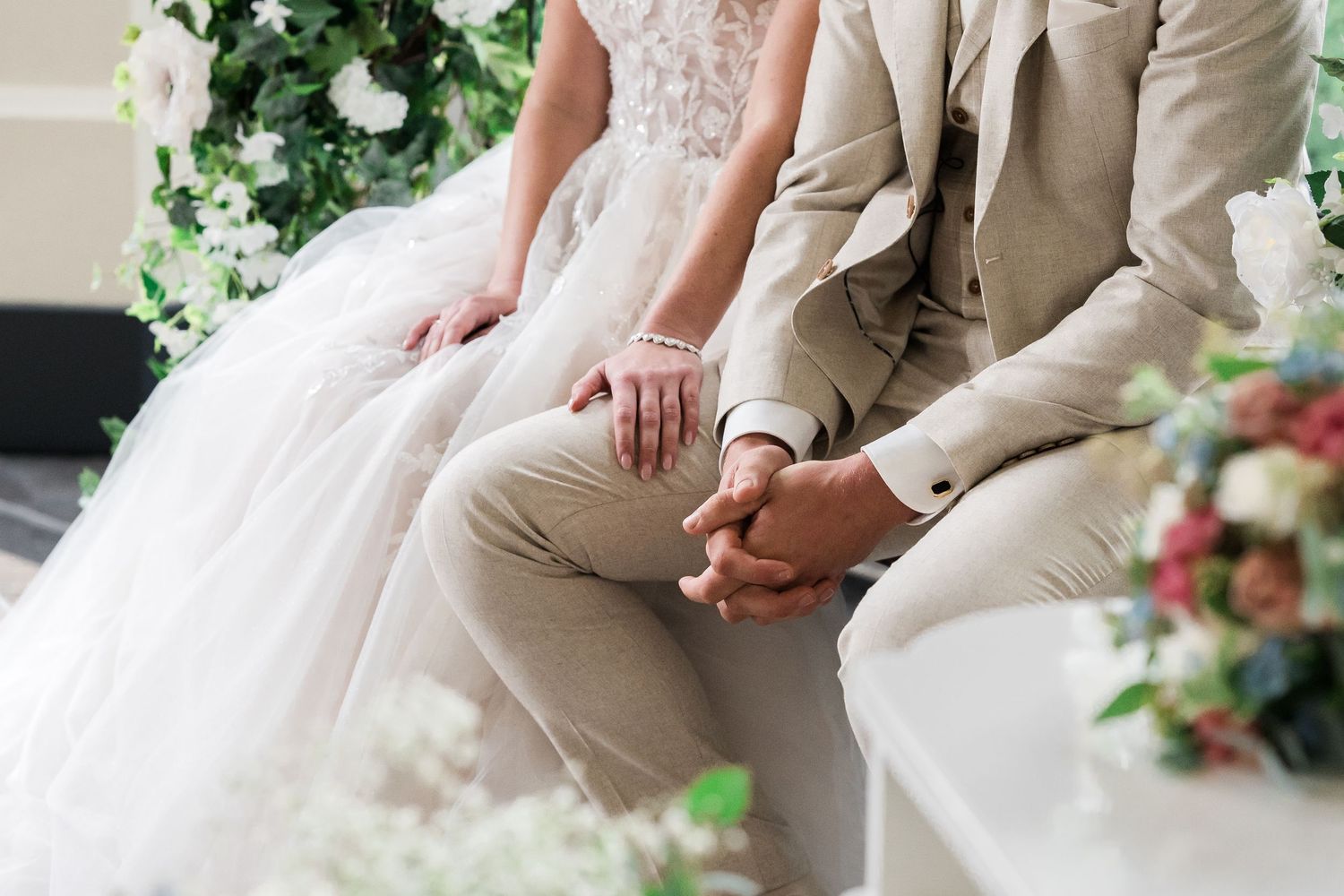 Trouwringen op schoot tijdens ceremonie op oranjerie sandenburg met christelijke trouwfotograaf