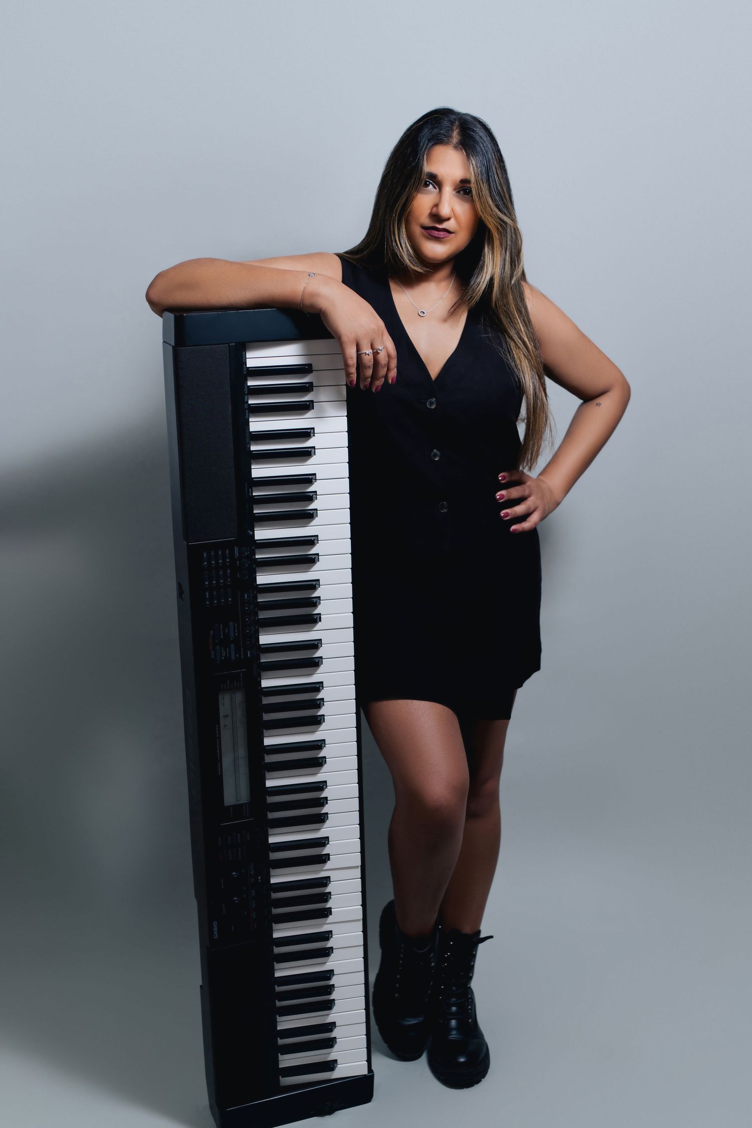 Artistic photo series showing poses with a black digital piano against a gray studio backdrop.