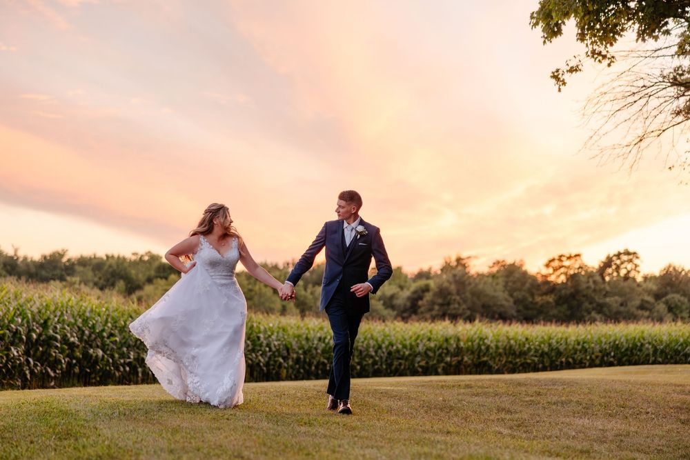 Sunset wedding portraits against a rural cornfield backdrop with soft orange sky.