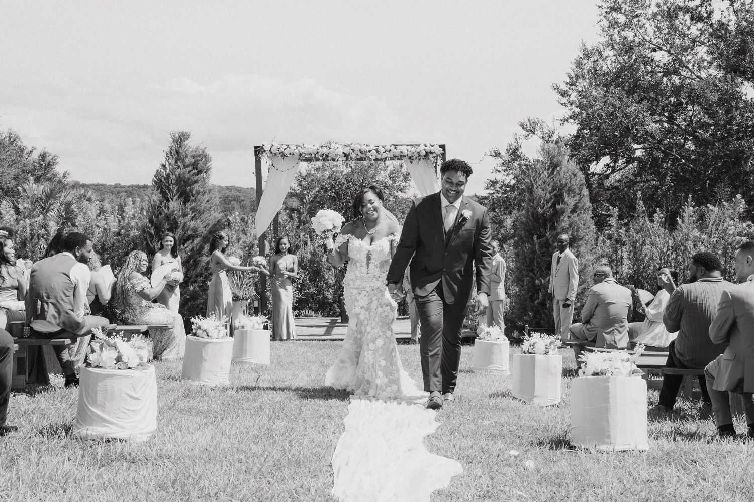 Black and white panoramic view of wedding guests gathered outdoors for a celebration.