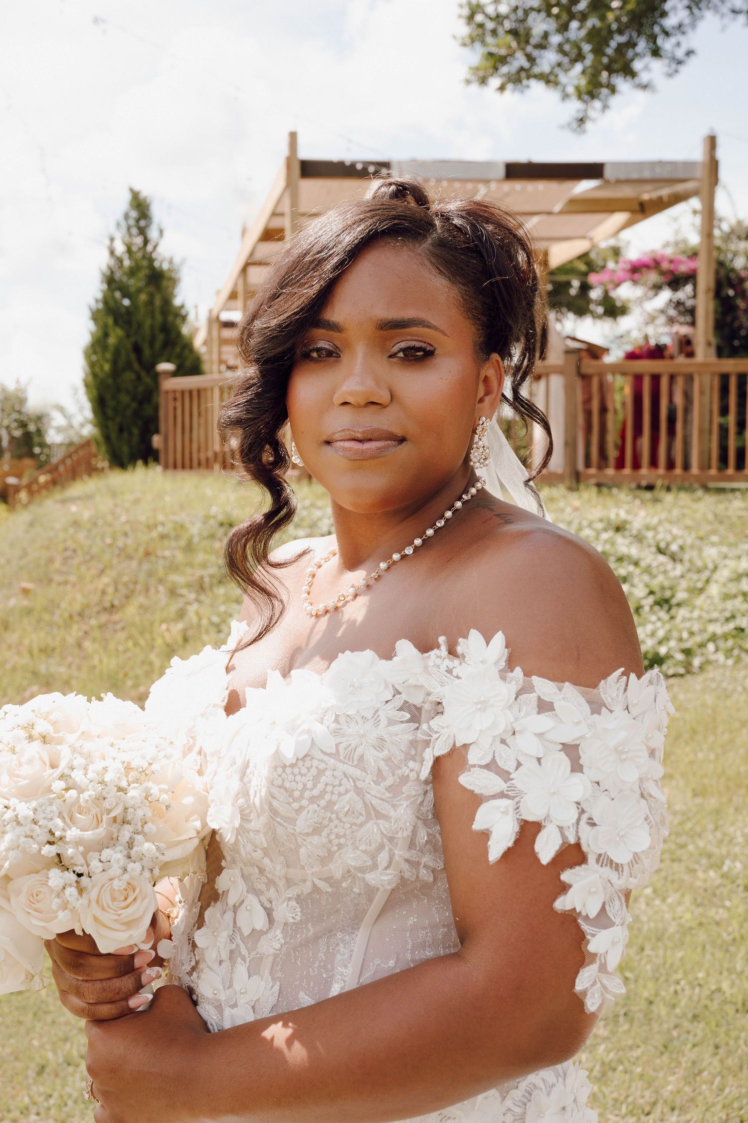Elegant white lace wedding dress with floral appliques and off-shoulder design.
