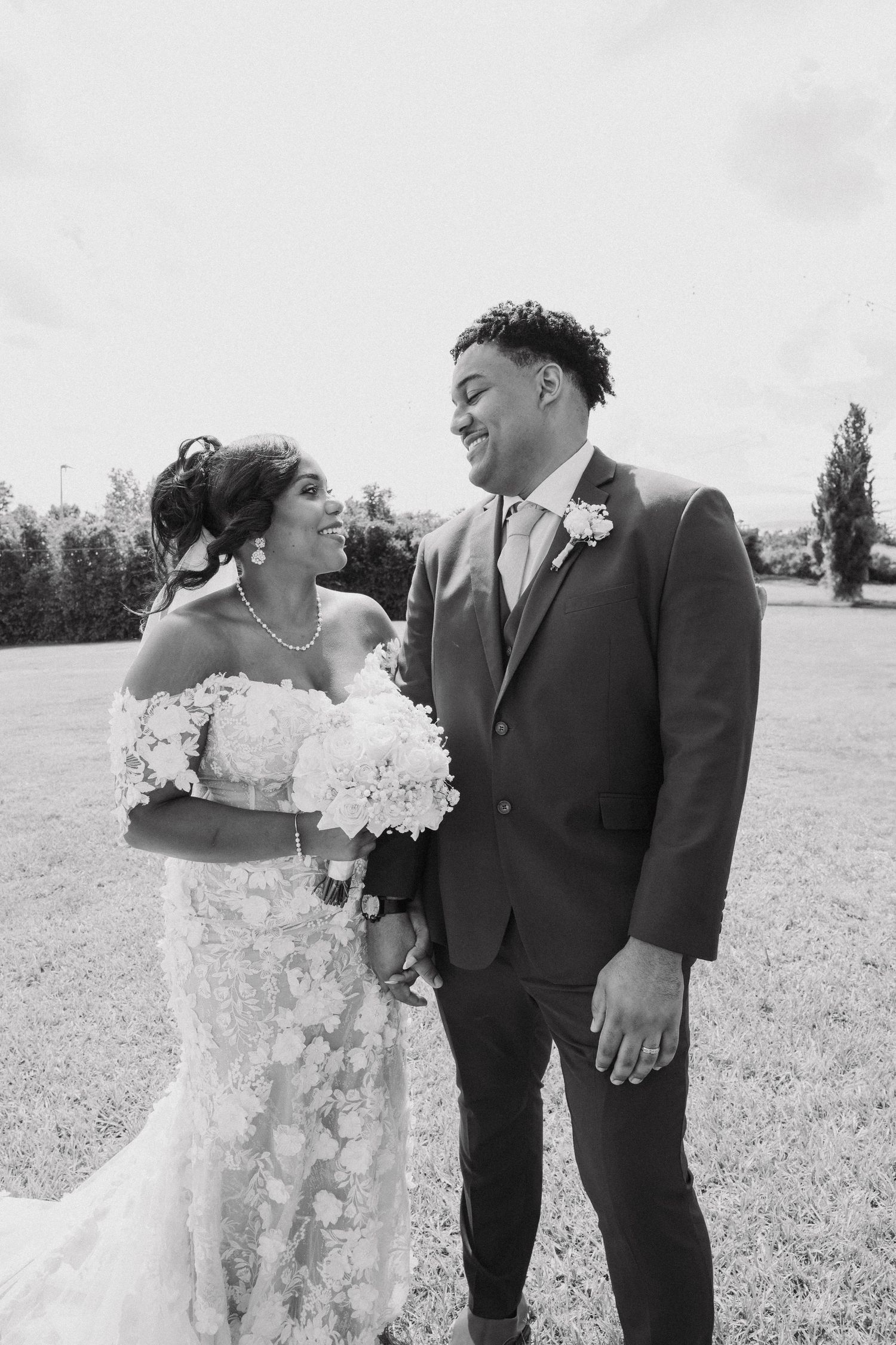 A happy couple shares joyful moments in a field during their wedding photoshoot.