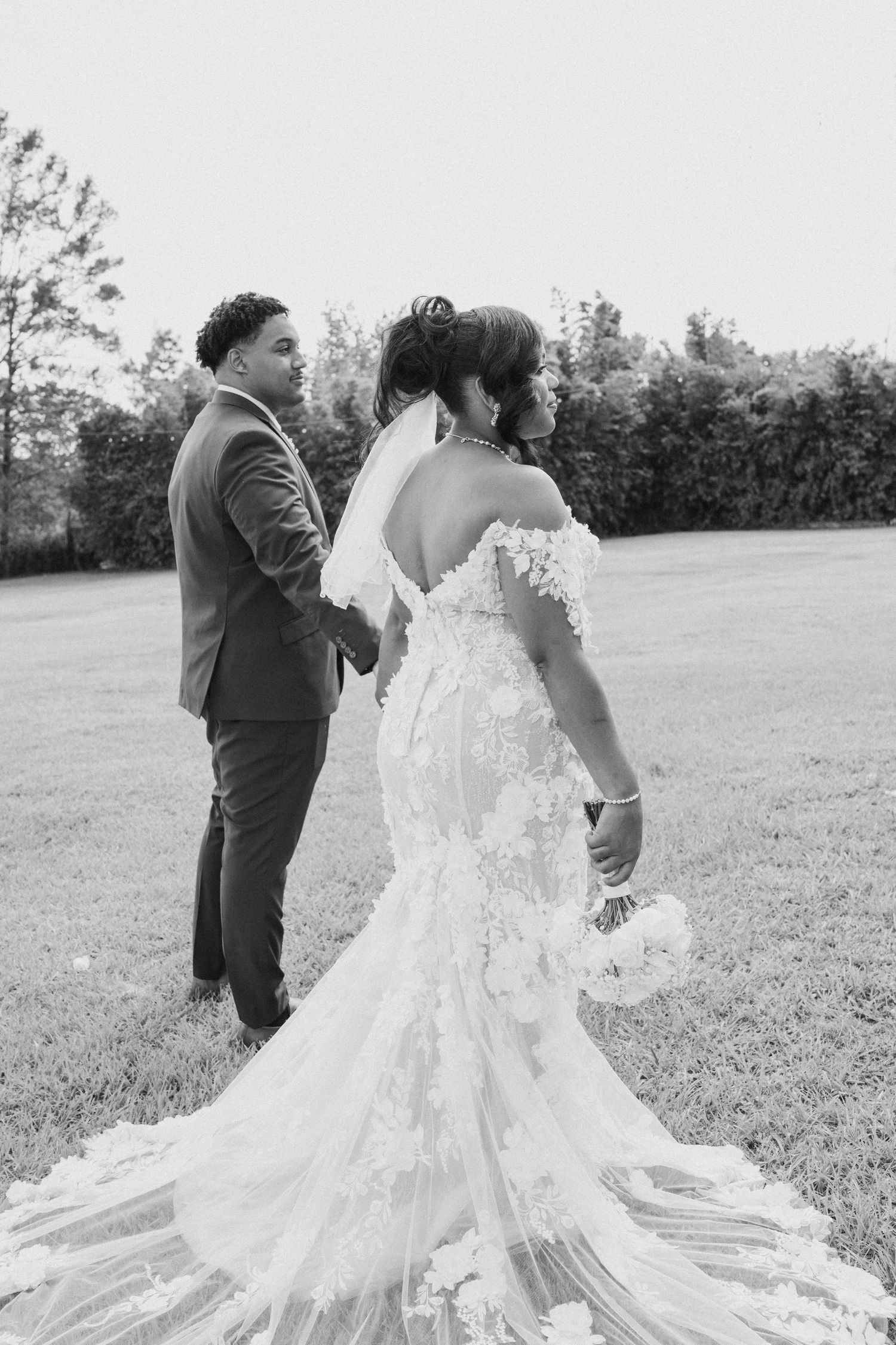 A wedding portrait showing the intricate details of a lace wedding gown with a flowing train.