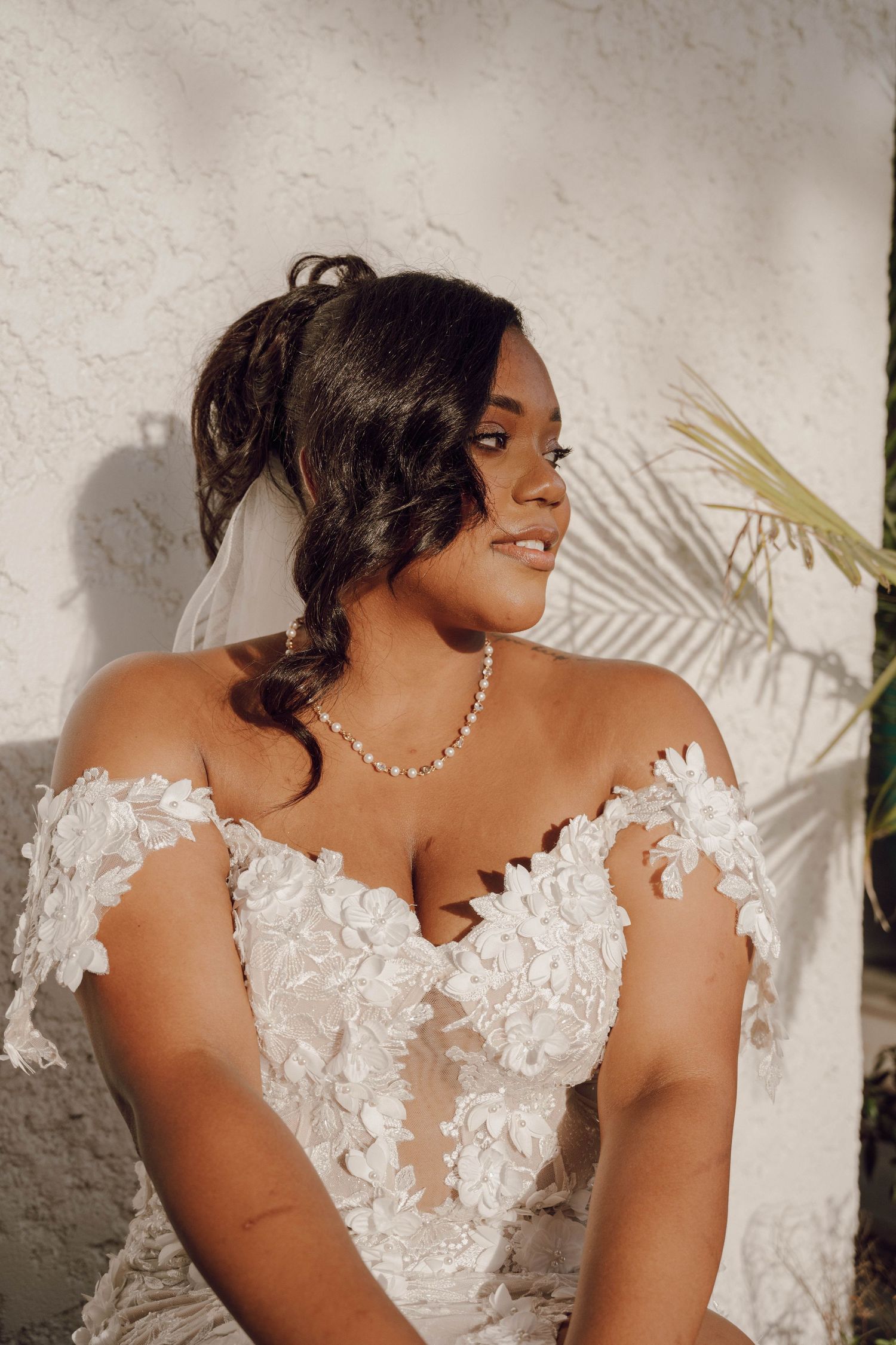 Close-up details of a bride's off-shoulder wedding gown with intricate white lace appliques.