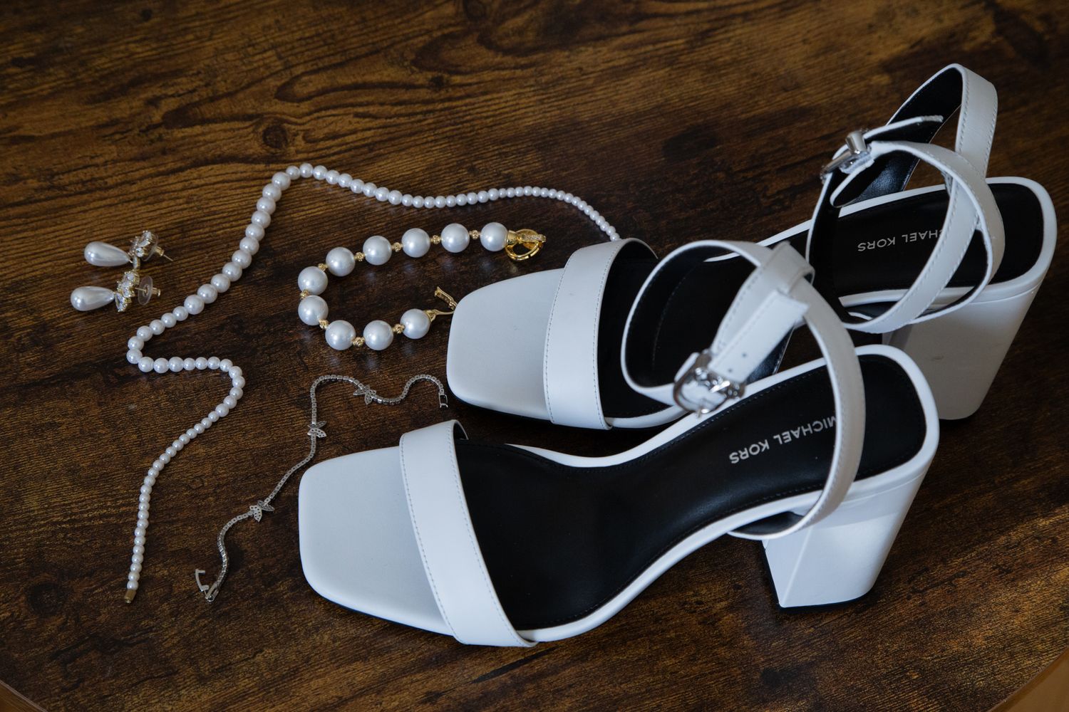 Photographie de détails de mariage mettant en valeur les alliances, les accessoires, les souliers et les fleurs, capturés avec une approche