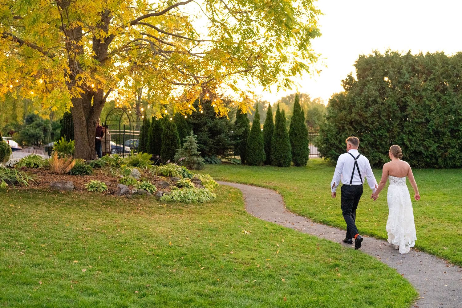 Wedding party members gather outdoors during a fall ceremony with golden leaves in the background.