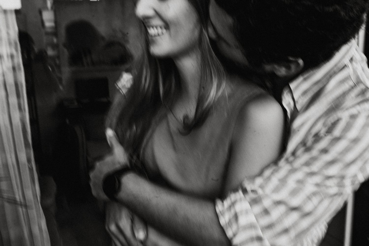 A blurred black and white candid photo shows two people embracing in an intimate moment.