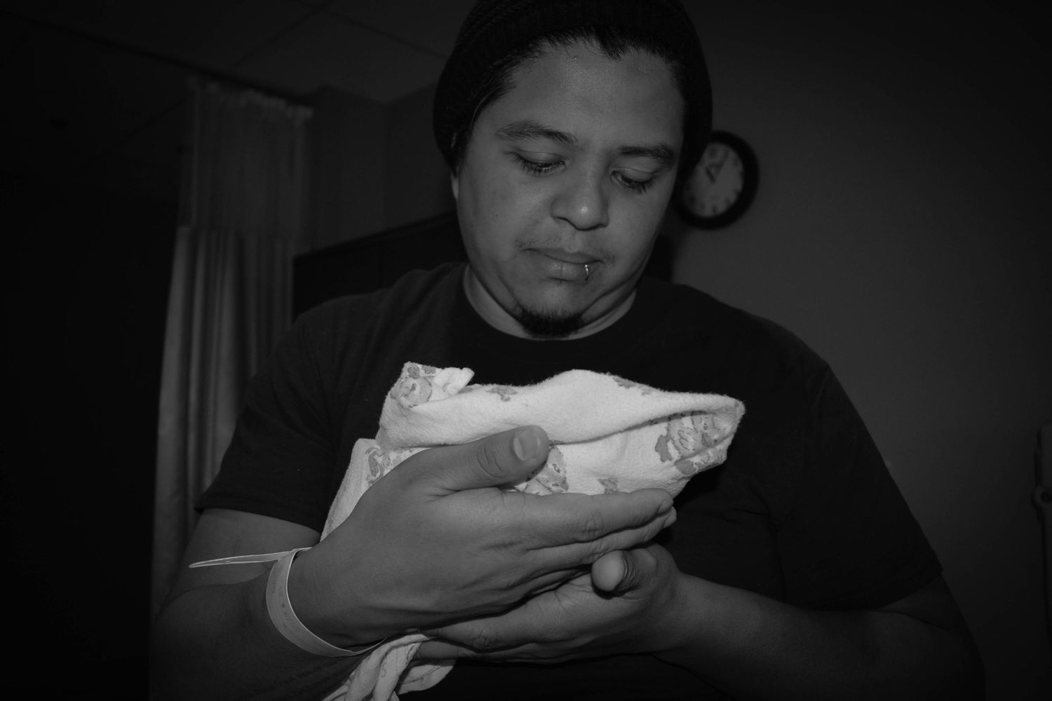 Series of black and white photos showing someone holding a baby in dim lighting.
