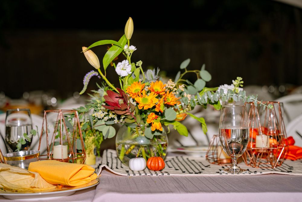 A long banquet table decorated with colorful floral arrangements, glassware, and candles for an elegant dining event.