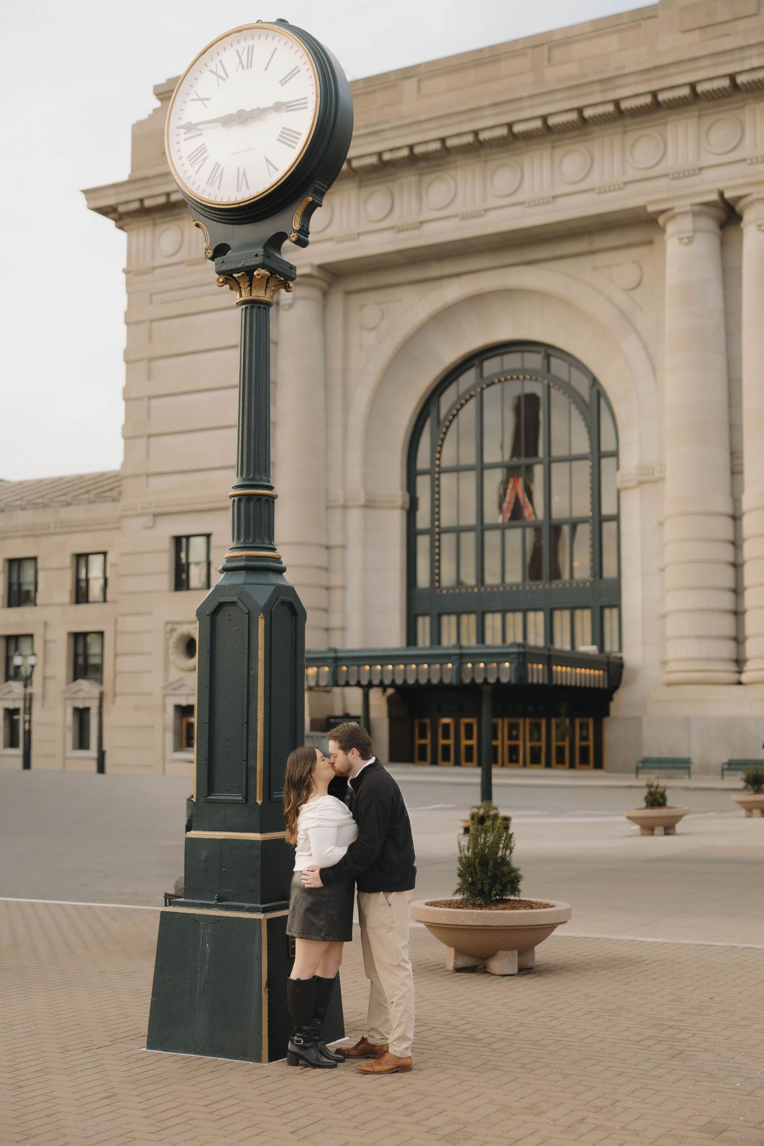Romantic engagement photos taken in front of a historic train station with ornate clock towers.