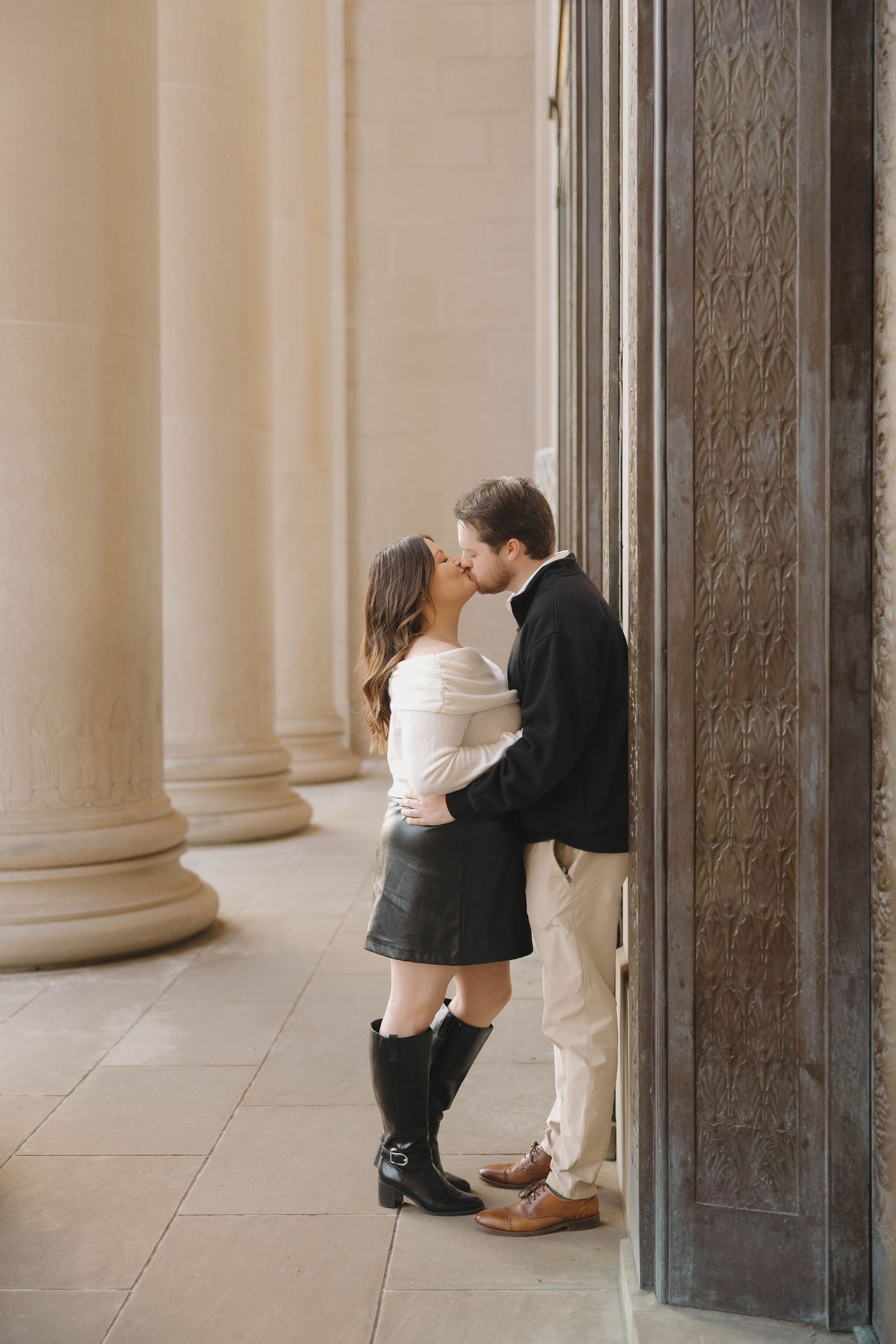 A romantic sequence captured between classical columns in an elegant architectural setting.