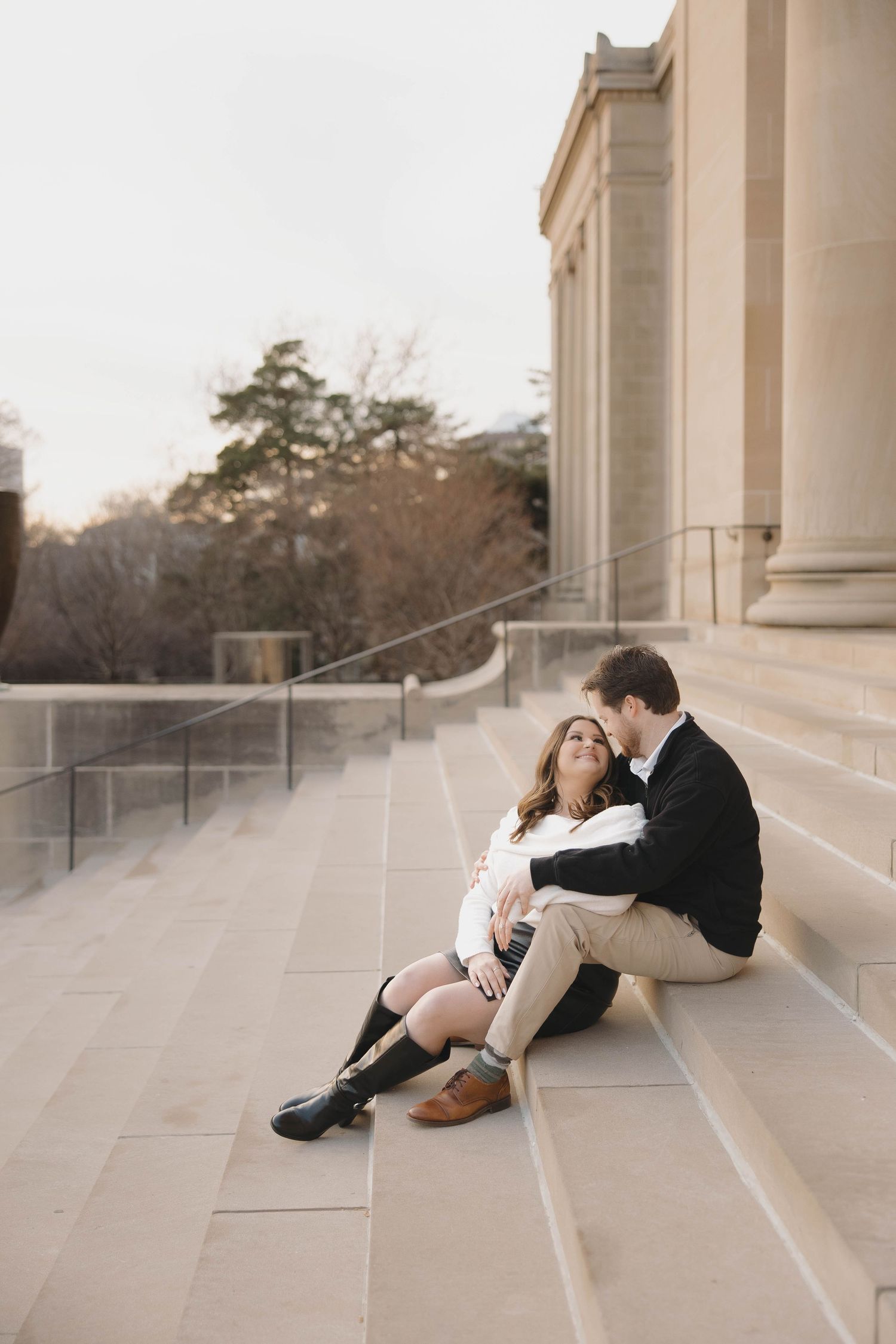 Couple sitting together on marble steps at sunset in a romantic architectural setting.