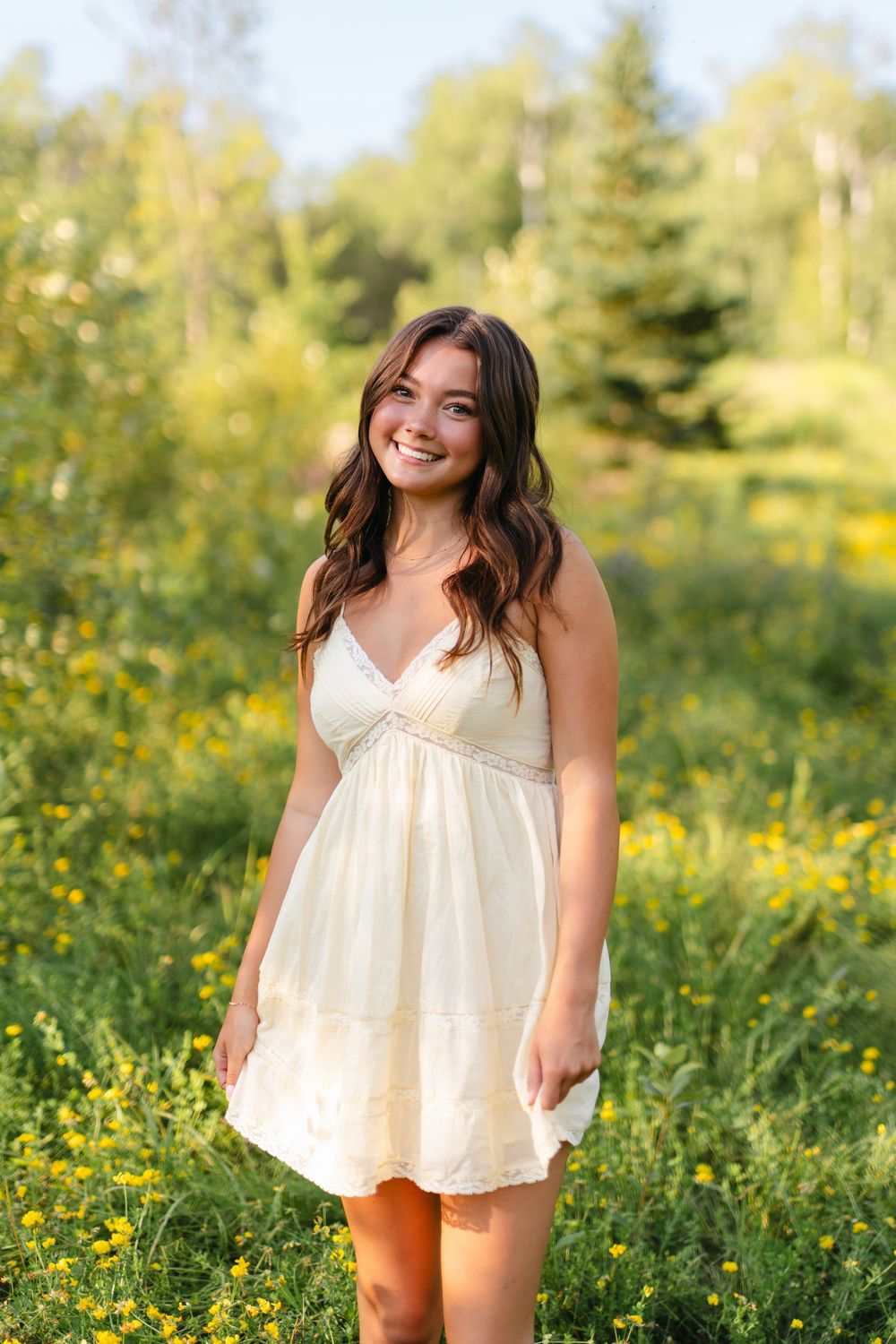 Summer portrait session in a blooming wildflower field with white flowy dress.