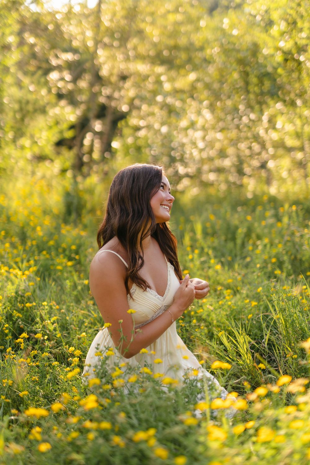 A white dress stands out against vibrant yellow wildflowers in a sun-drenched meadow during golden hour.