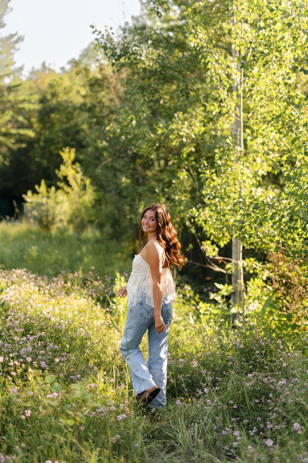 Candid portraits in a wildflower meadow with soft natural lighting and green foliage.
