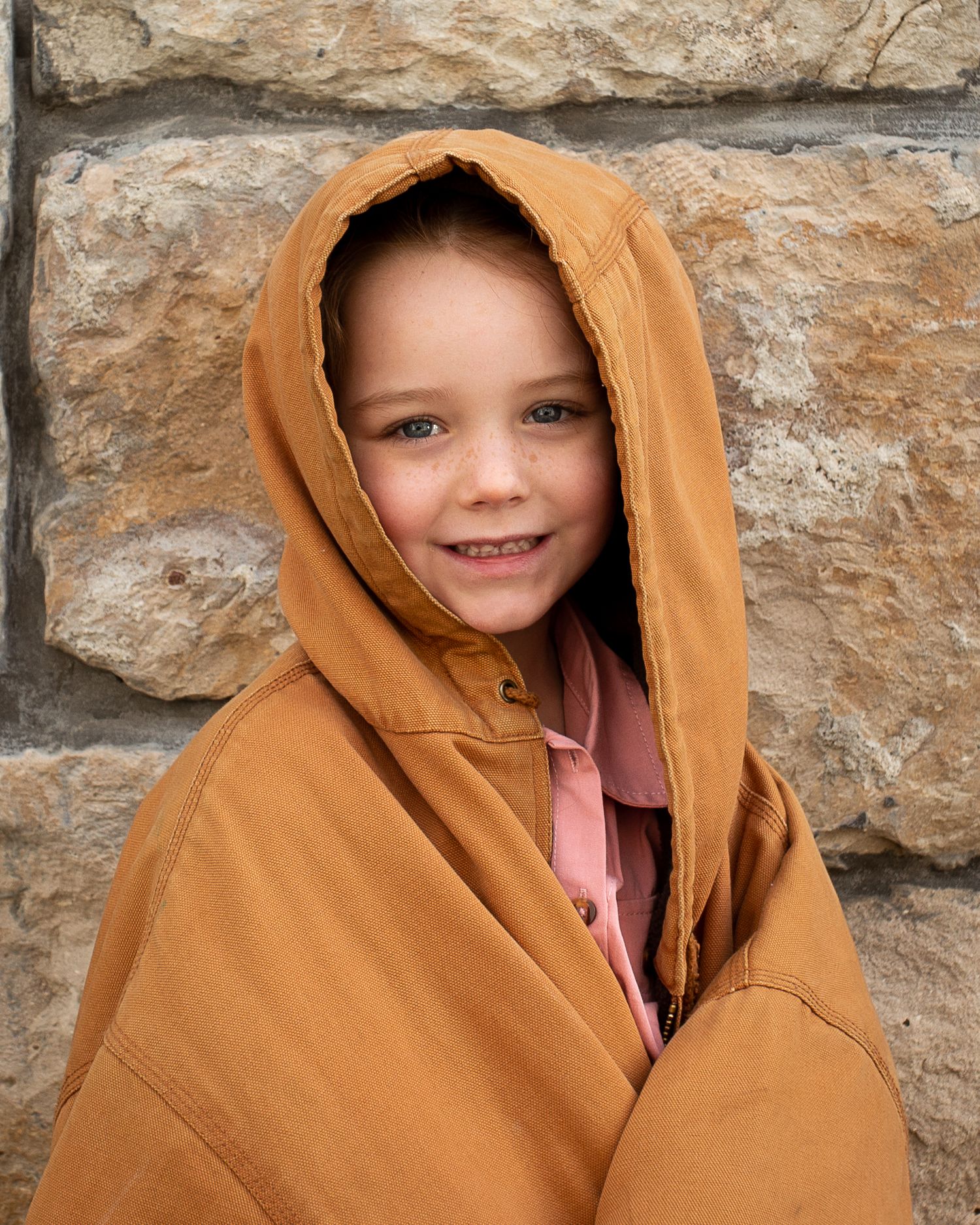 A sequence of four photos showing a person wrapped in a brown blanket against a stone wall background.