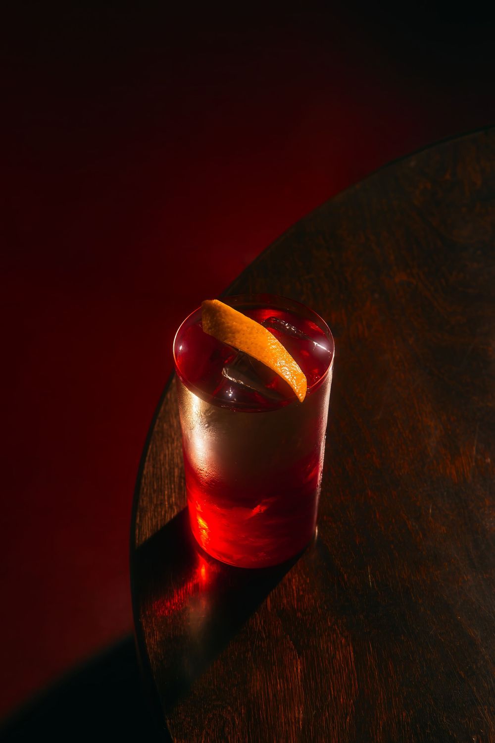 A dramatic series of red-tinted photographs showing a shiny apple being sliced into segments against a dark background.