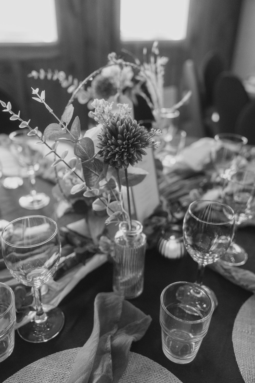 Elegant black and white table setting with delicate floral arrangements and glassware for a wedding reception.