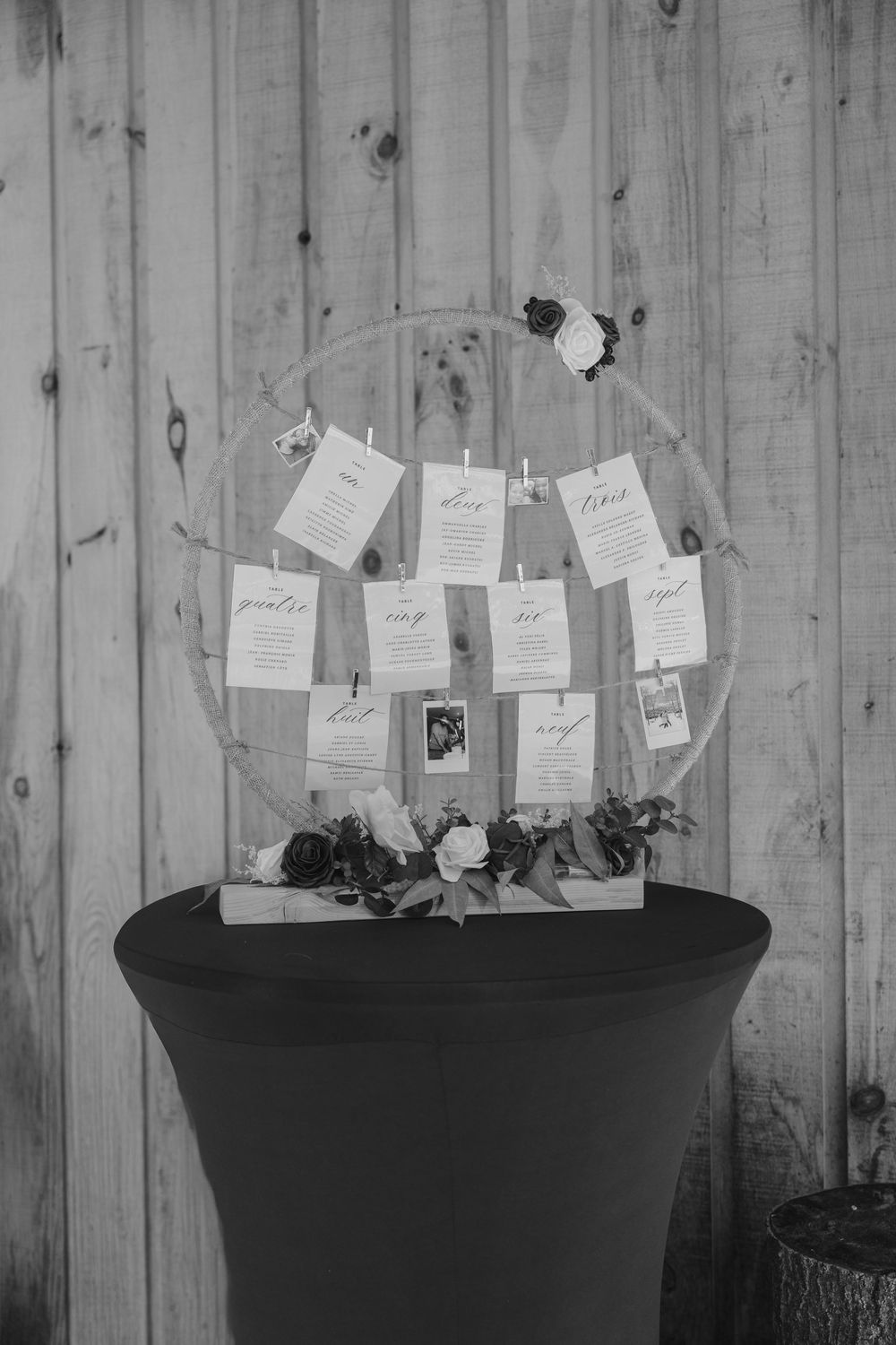 Black and white photo of wedding cards displayed on decorative stands against wooden wall.
