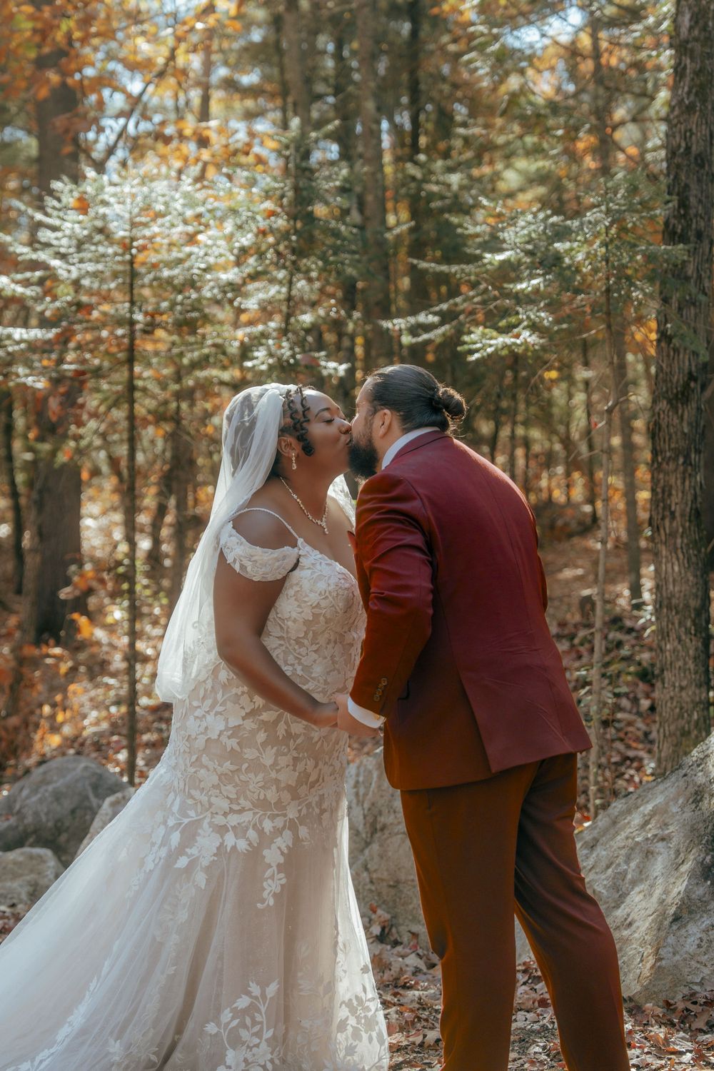 Romantic autumn wedding photoshoot in a forest with fall foliage and natural rock formations.