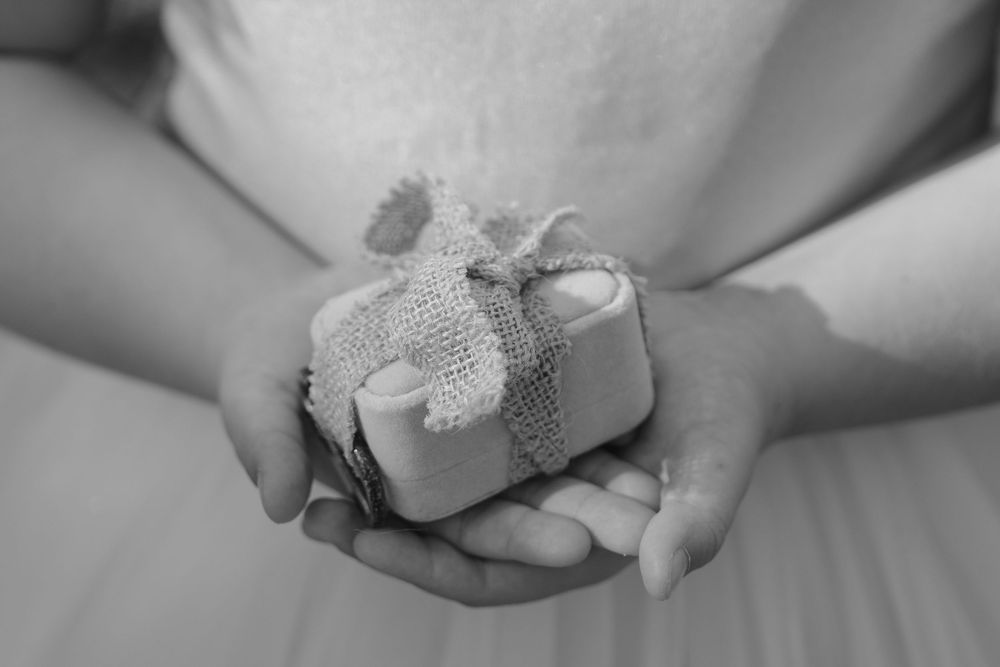 Close-up black and white photo of hands exchanging rings during a wedding ceremony.